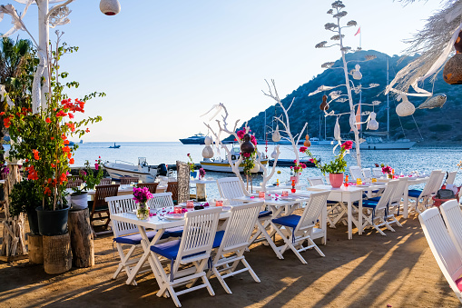 Restaurant and bougainvillea flowers on beach in Gumusluk, Bodrum. Colorful chairs, tables and flowers in Bodrum town near beautiful Aegean Sea.