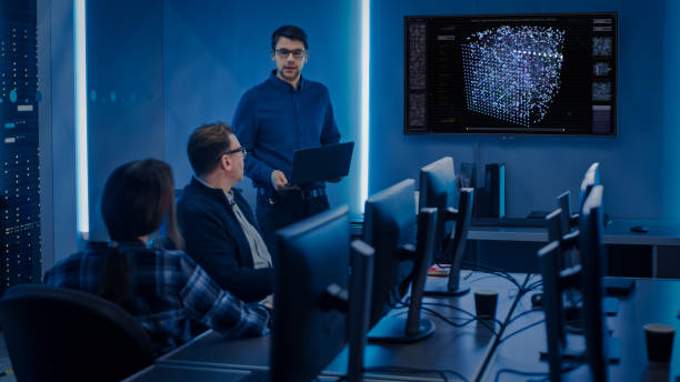 istock Team of Professional IT Developers Have a Meeting, Speaker Talks about New Blockchain Based Software Development Shown on TV. Concept: Software Development, Deep Learning, Artificial Intelligence, Data Mining 1195775369