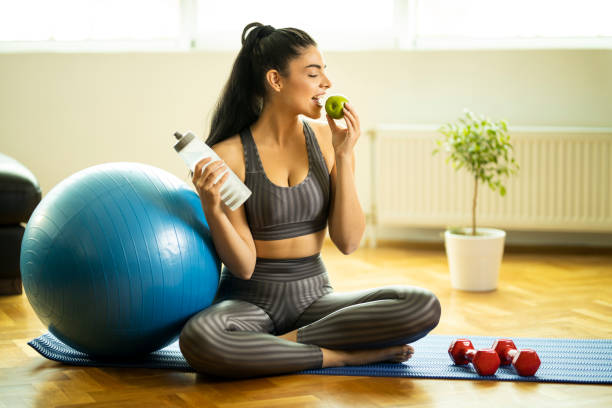 istock Woman drinking water, eating apple and exercising 1195775583