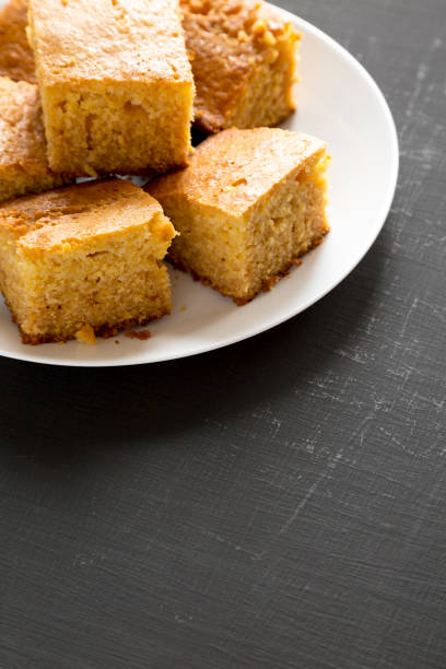 istock Homemade Sliced Cornbread Ready to Eat on a white plate on a black background, side view. Copy space. 1195777977