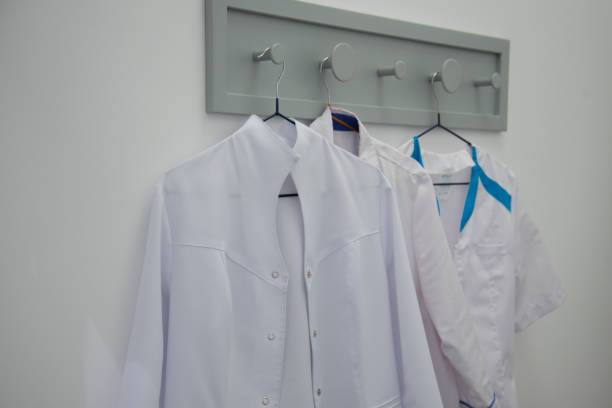 istock A white medical gown hangs on a hanger. White background. Concept. 1195778944