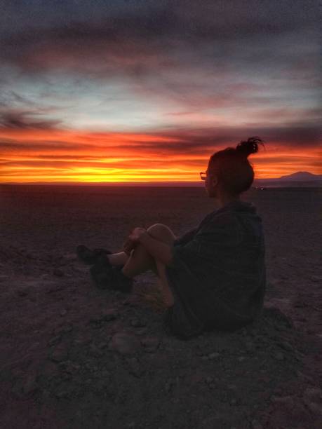 Girl watching sunset at Laguna Tebinquiche, Atacama Desert, Chile, South America. stock photo