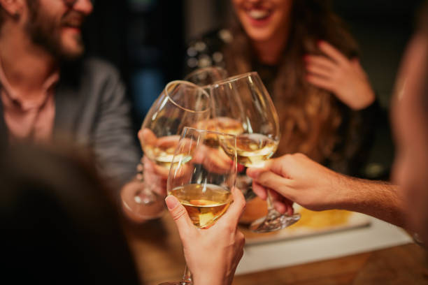 istock Best friends sitting in restaurant for dinner and making a toast with white wine. On table is food. 1195779958