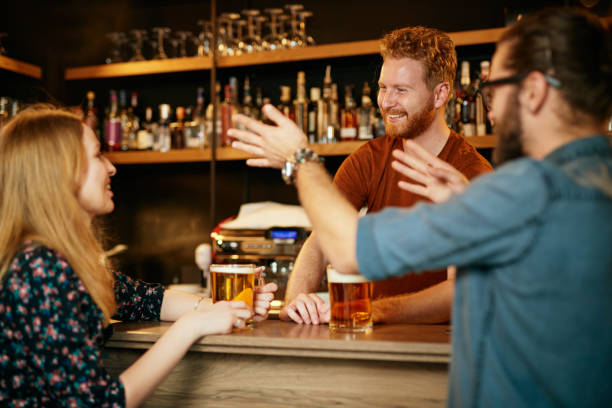 istock Cheerful friends leaning on bar counter, drinking beer and chatting with bartender. Night out. 1195780083
