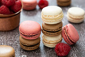 Heap of macarons isolated on dark background. Healthy cake dessert made from almond flour. Raspberry macaroons cookies.