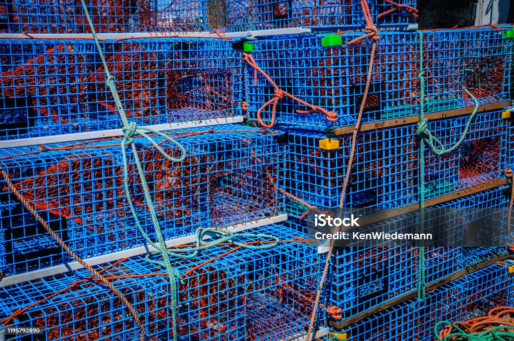 Stack of Lobster Traps Orange colored ropes help secure blue wire mesh lobster traps onto the rear deck of a lobster boat at Sandwich Marina on Cape Cod. Blue Stock Photo
