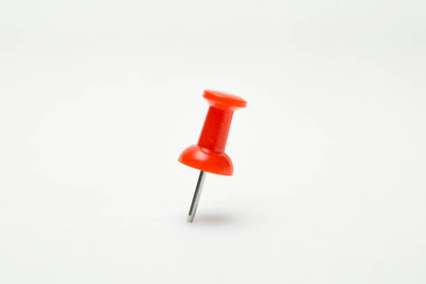 Two red push pins are placed on a bold orange background, showcasing simplicity.