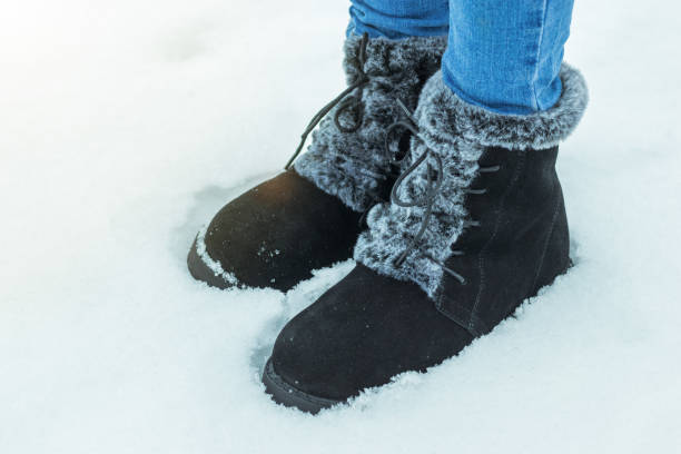 istock Women's feet in warm boots in deep snow. 1195822946