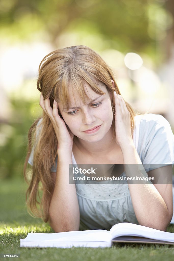 Adolescente feminino estudante estudar no parque com perplexidade que ouvimos - Foto de stock de Estresse emocional royalty-free
