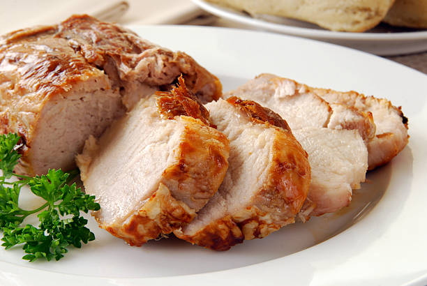 Slices of hot pork roast on a plate with herbs on the side Sliced roast pork on a plate pork stock pictures, royalty-free photos & images