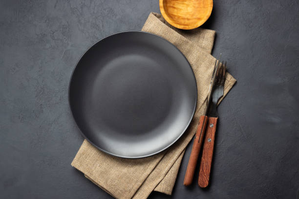 black plate and cutlery over napkin on dark background. - napkin black blank ideas imagens e fotografias de stock
