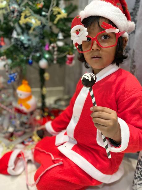 istock Young Boy from India Celebrates his Christmas while Sitting under the Christmas Tree. 1195835450
