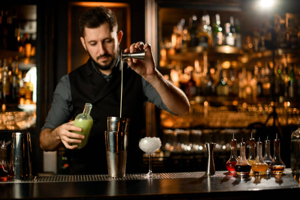 istock Bartender pouring cocktail with liquor using jigger and shaker 1195836851