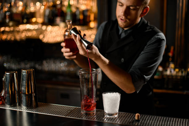 istock Bartender pouring liquor from jigger to glass 1195836873