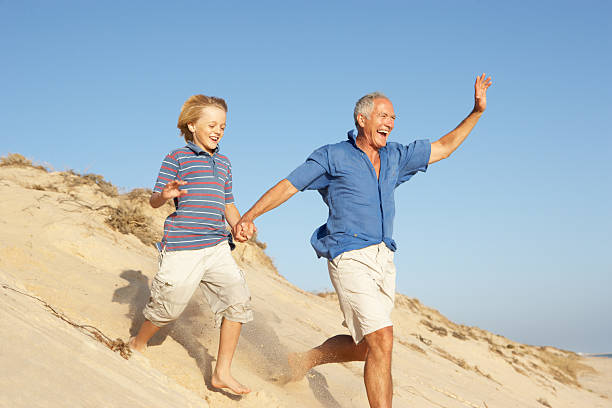 istock Grandfather And Grandson Running Down Sand Dune 119583715