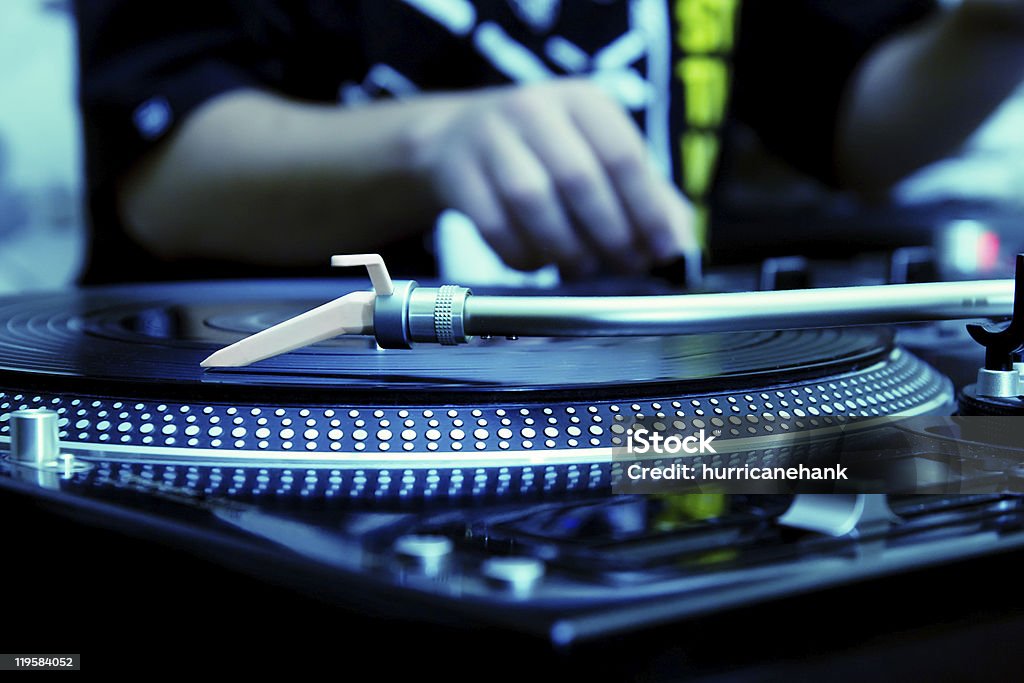 DJ playing music from vinyl record Focus on the professional turntable with a DJ adjusting the volume on controller Adjusting Stock Photo