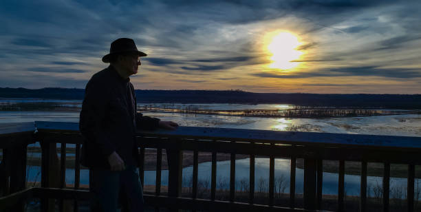Older man in hat looking at sunset