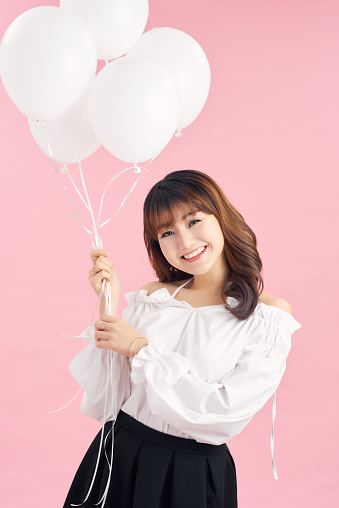 Young beautiful asian girl holding balloons. Studio. Woman holding white balloons. Birthday.