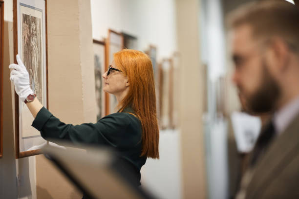 Young woman working as art manager at gallery she preparing for the exhibition together with man