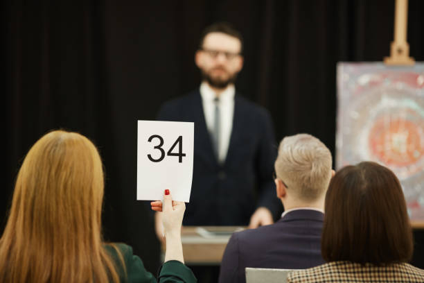 istock Woman sitting at auction 1195845139