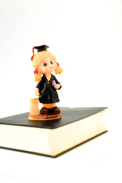istock Graduation doll on the book. 1195873657