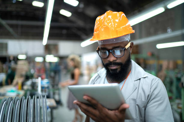 ingénieur utilisant la tablette et travaillant dans l'usine - ouvrier à la chaîne photos et images de collection