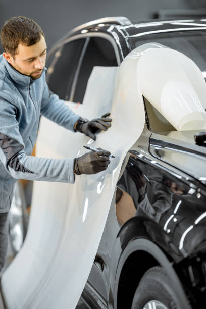 Filming car body at the vehicle service Man preparing protective film for sticking on a car body, marking it to with a pen at the vehicle service station. Concept of car body protection with special films scuff marks photos stock pictures, royalty-free photos & images