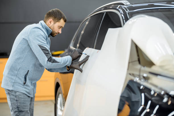 Filming car body at the vehicle service Man preparing protective film for sticking on a car body, marking it to with a pen at the vehicle service station. Concept of car body protection with special films scuff marks photos stock pictures, royalty-free photos & images