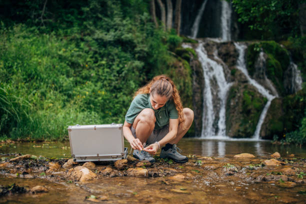 istock Woman biologist taking a water sample in nature 1195889615