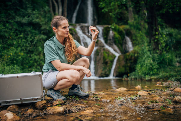 istock Lady biologist taking a water sample by the waterfall 1195889667