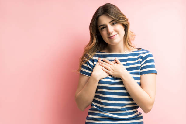 istock Beautiful Female Smiling While Touching Heart In Studio 1195891130