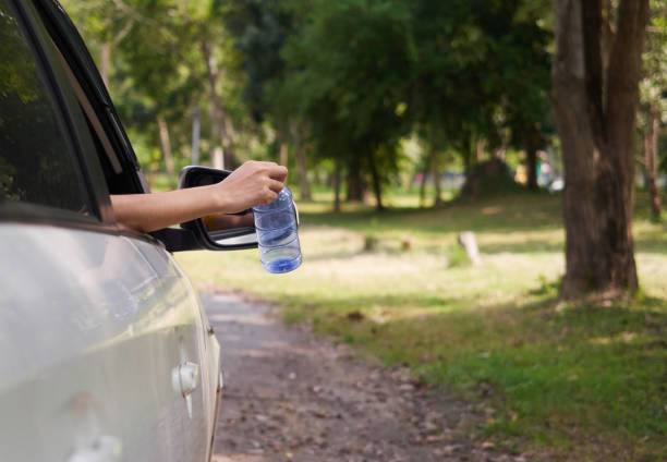 istock Close up Hands throwing empty plastic bottle out of car window. 1195893318