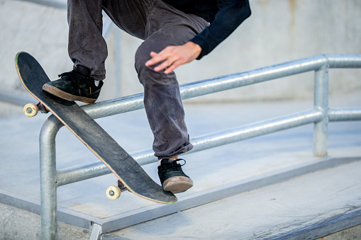 Young Adult Skateboarder Sliding on Rail.