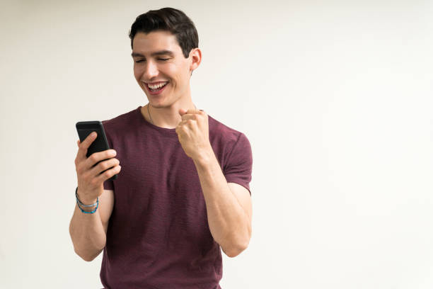 Excited Man Enjoying News On Mobile Phone In Studio
