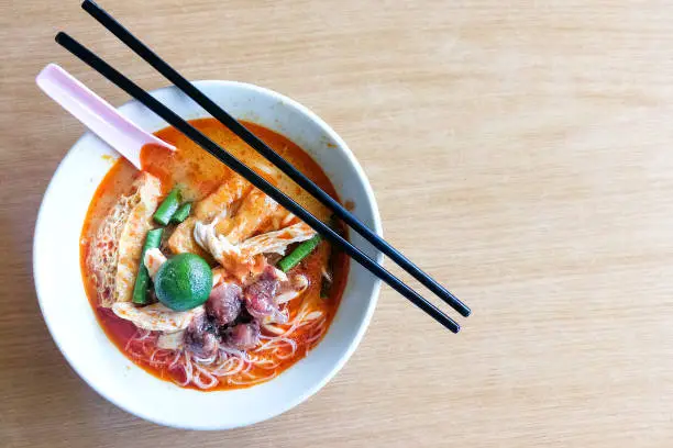 Photo of Overhead view bowl of curry laksa noodle soup with cockerel