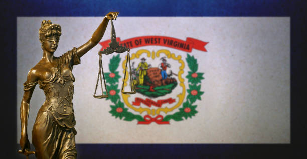 Lady Justice before a West Virginia state flag Close-up of a small bronze statuette of Lady Justice before a flag of West Virginia. west virginia us state stock pictures, royalty-free photos & images