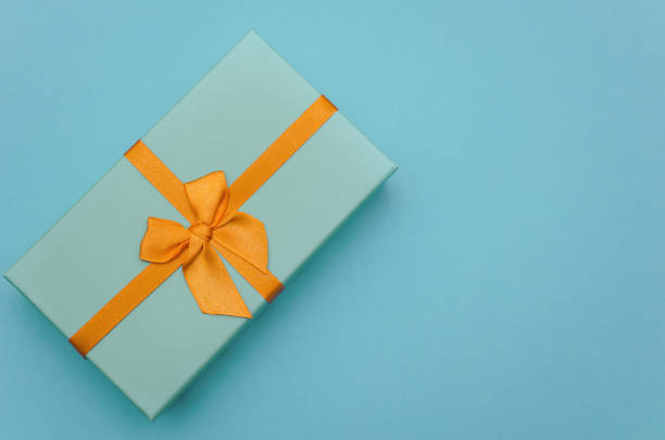 istock Blue gift with an orange ribbon on a blue background. View from above 1195911948