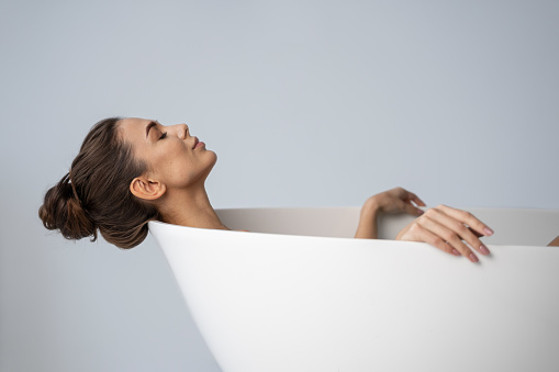 Side view of a girl relaxing in a bath with her eyes closed
