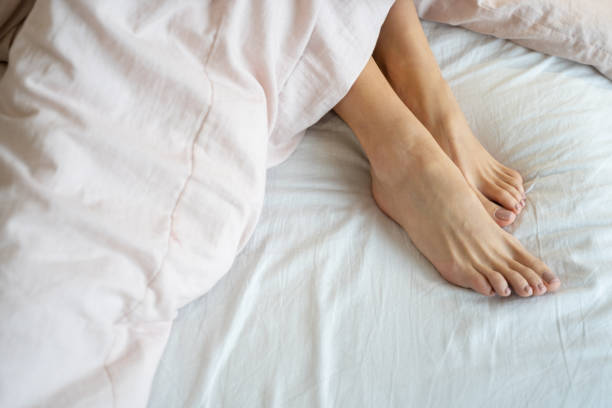 istock Woman with bare feet relaxing in bed 1195914370
