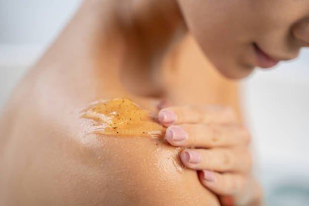 Young Caucasian lady using a body cleanser Cropped photo of a girl applying an exfoliating body gel shower gel stock pictures, royalty-free photos & images