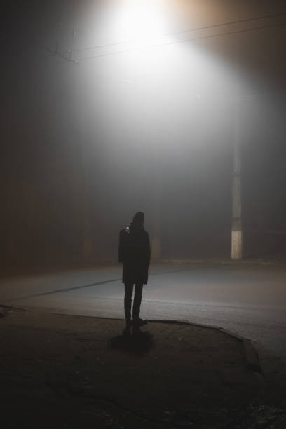 uma pessoa que está perto da estrada em uma cidade nevoenta na noite. - smog city pollution town - fotografias e filmes do acervo