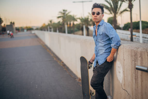 istock Handsome guy with skateboard standing on the street 1195915668