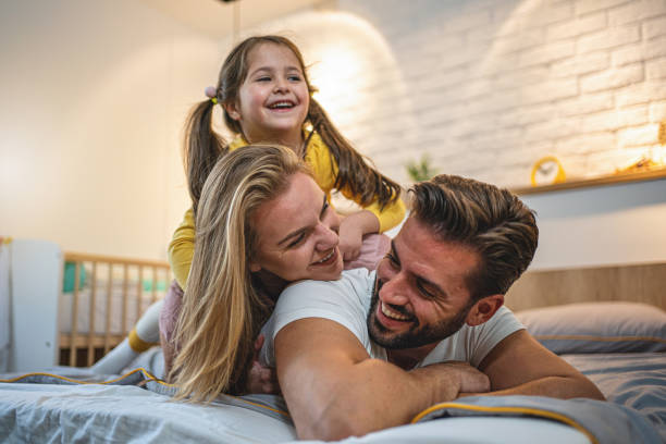 istock Cheerful child playing in bed with young parents 1195916560