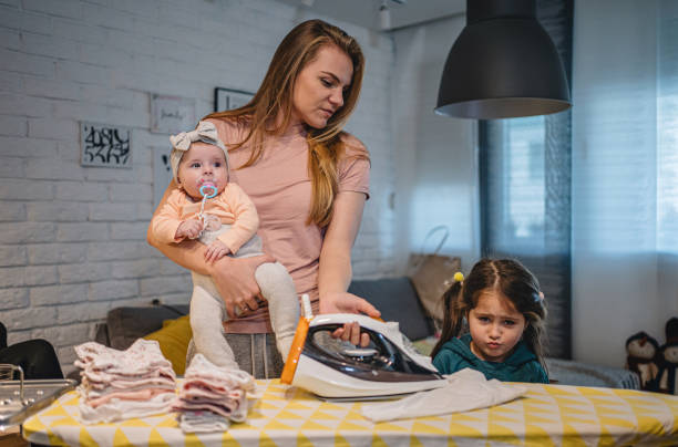 istock Young mother ironing while caring for two daughters at home 1195917370