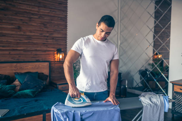 istock Dark-haired young man in white tshirt standing with iron in his hand 1195922578