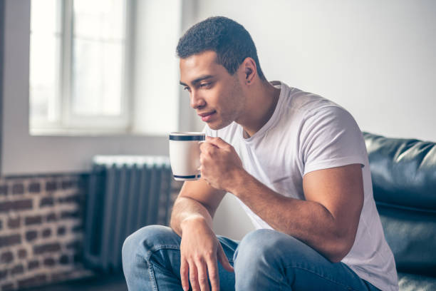 istock Guy thinking in a chair with a cup in his hand. 1195922602