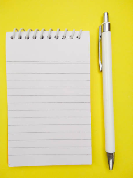 istock Spiral notepad diary and pen isolated on yellow colored background. 1195922880