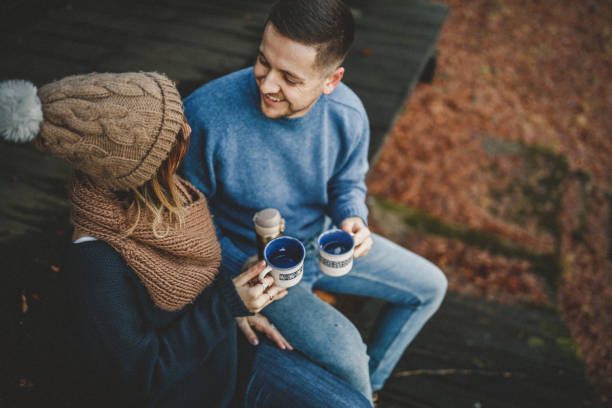 Couple drinking coffee in front of log cabin