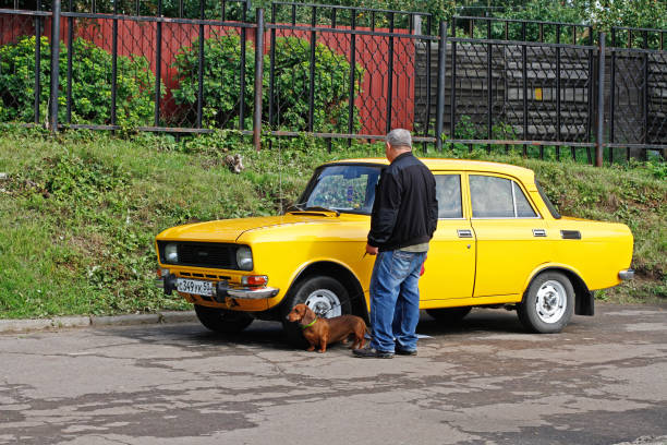 ein älterer mann mit dackel untersucht sowjetisches fahrzeug moskwitsch-412 beim festival "retrosummer" in pushkino - izhevsk stock-fotos und bilder