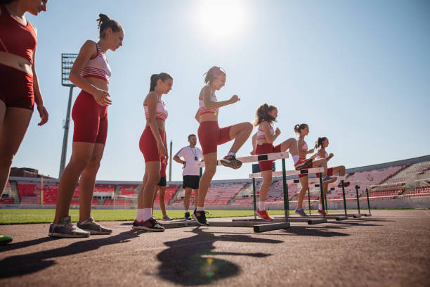 istock Female athletics team exercising hurdling on a stadium 1195930698